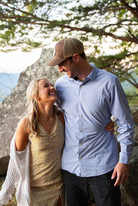 Couple smiling at each other on a mountain top after proposal.